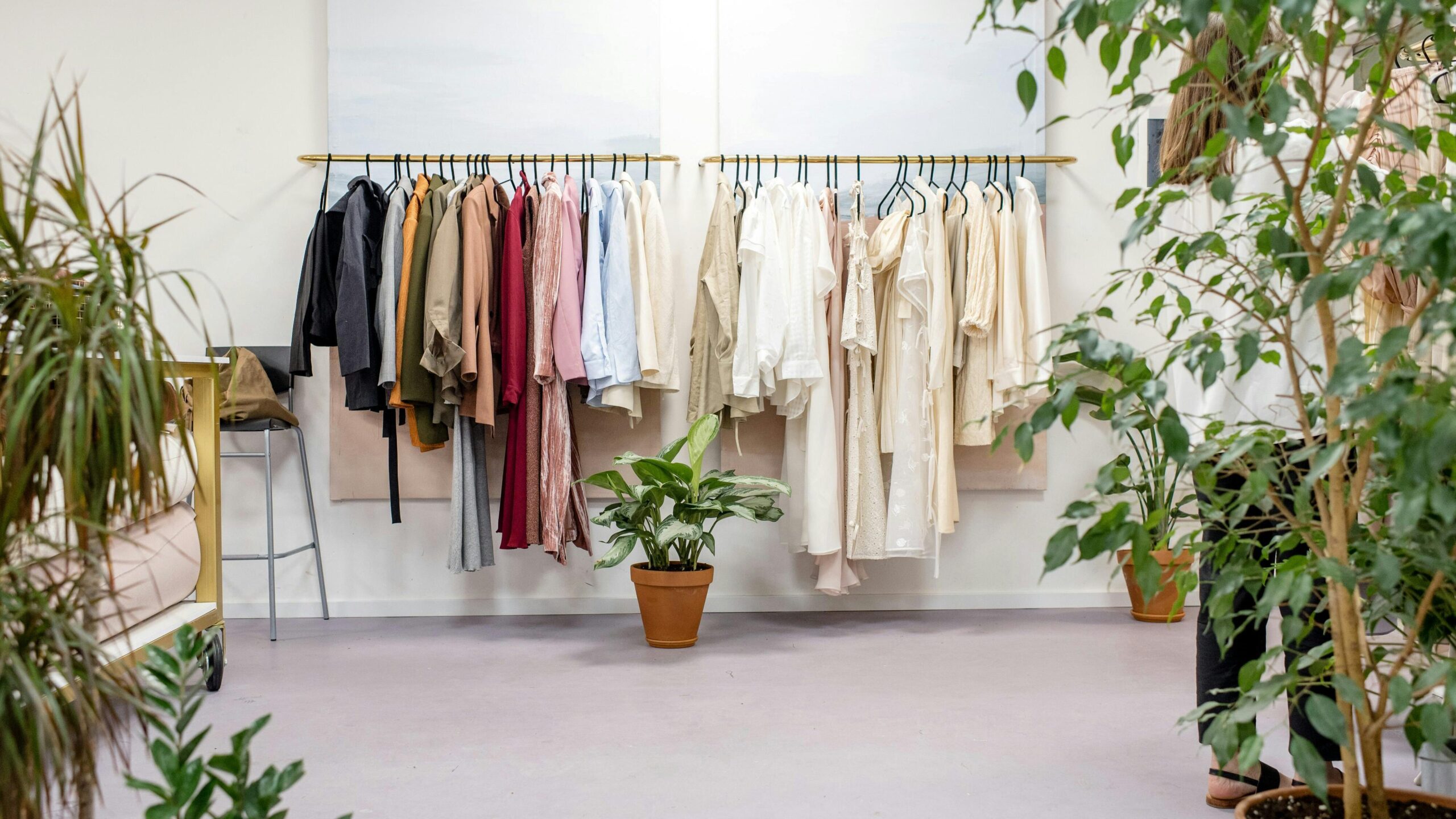 Chic fashion boutique showcasing vibrant clothing collection with lush indoor plants.